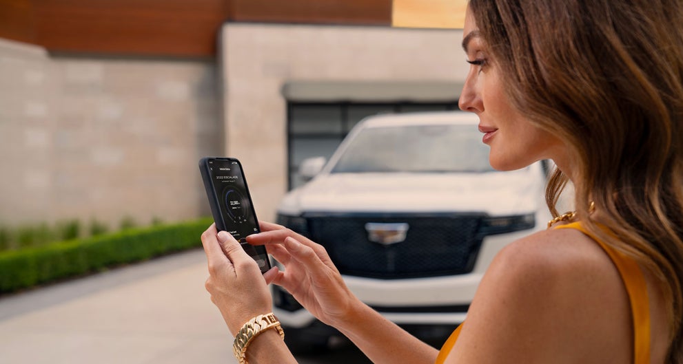 lady checking her mobile with a Cadillac vehicle background | Jessup Cadillac in CATHEDRAL CITY CA