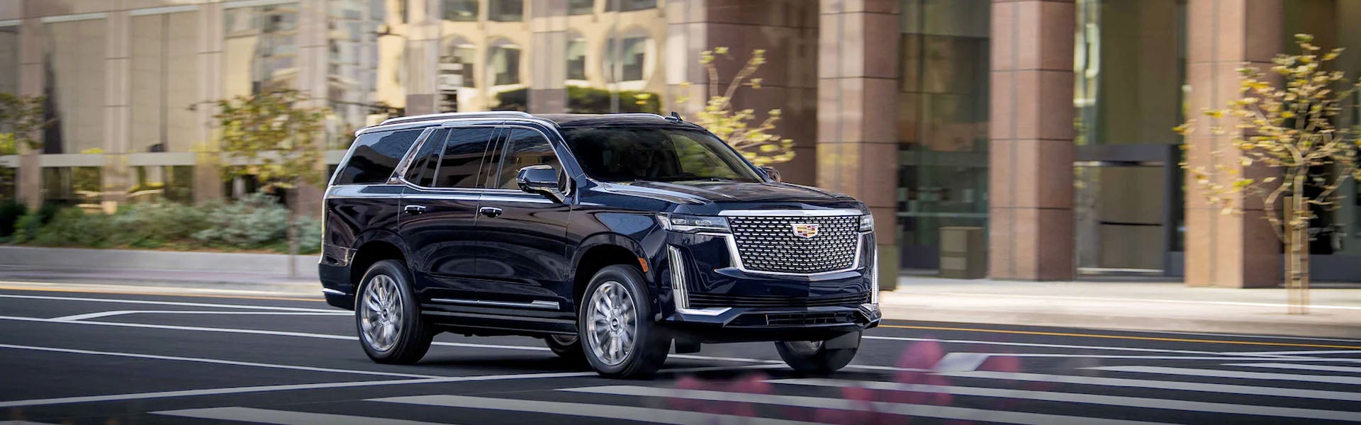 Black Cadillac Escalade driving through town on a nice and sunny day