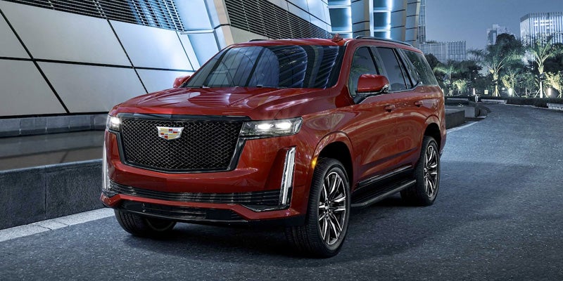 Red Cadillac Escalade parked next to a big building at night
