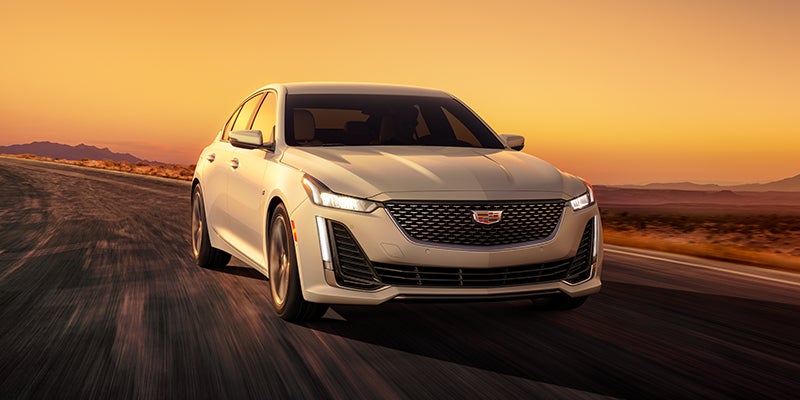 Cadillac CT5 driving down the road at high speed when the sun is setting