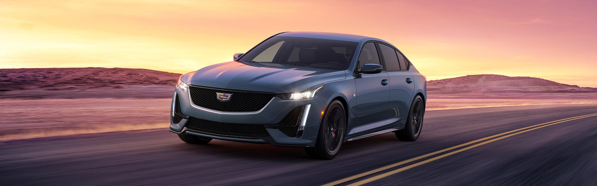 Cadillac CT5 driving at high speed on the road outside by a desert